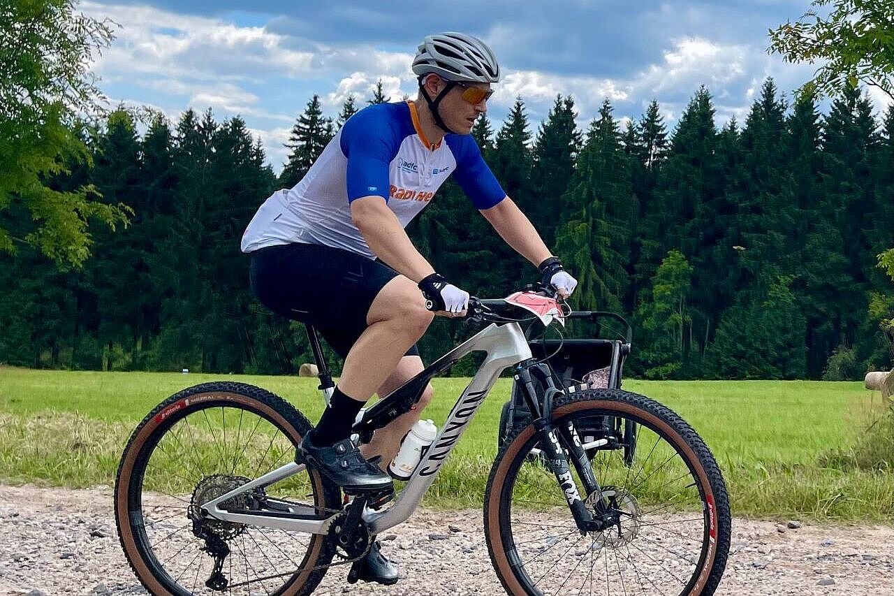 Schotterclimb Ein Mountainbiker in der Seitenansicht fährt einen Schotterweg hinauf.